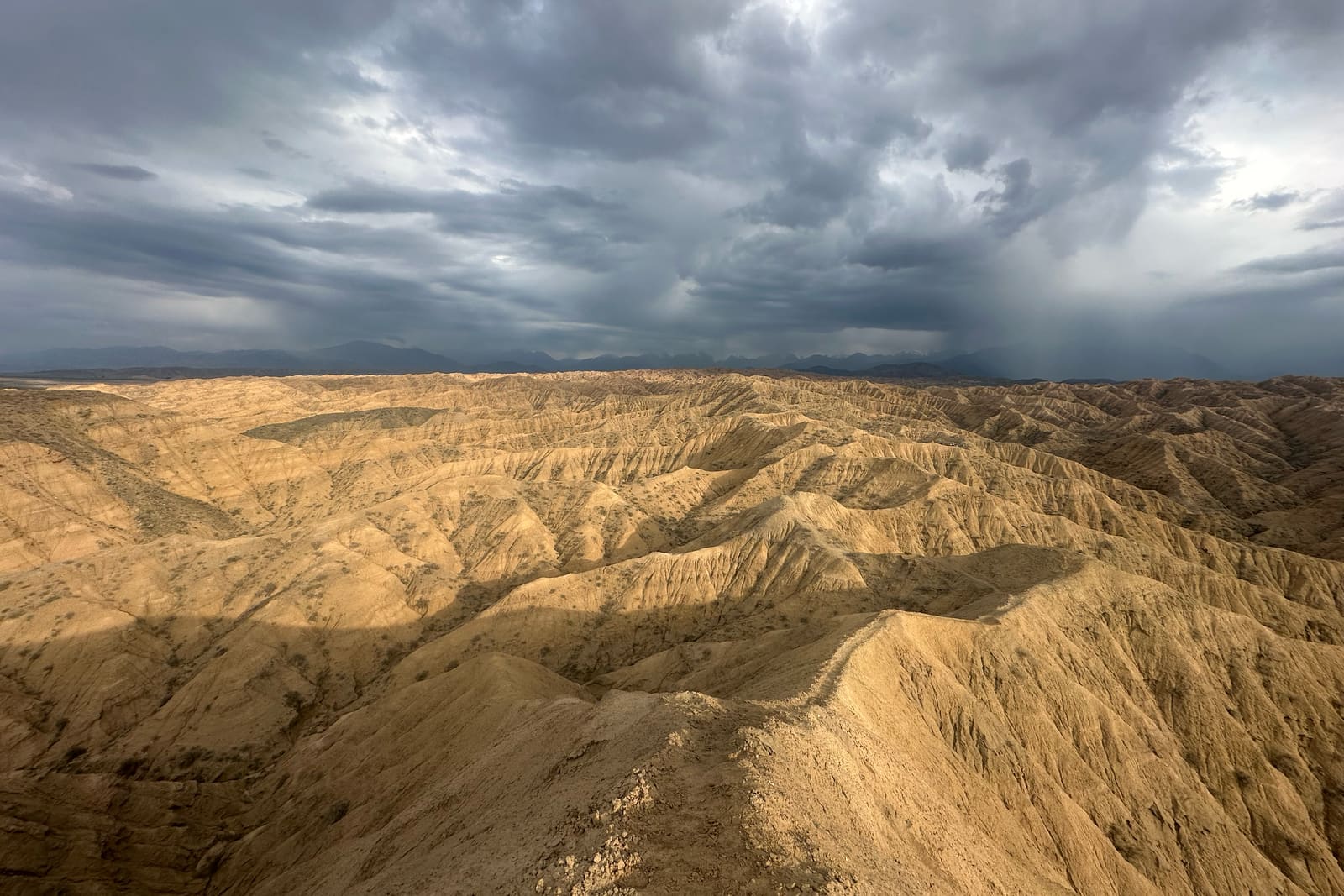Dešťové clony nad zvrásněnými zlatými badlands u jižního břehu Issyk-Kulu